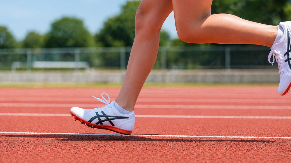 陸上トラックでスパイクを履いて走る中学生の足元